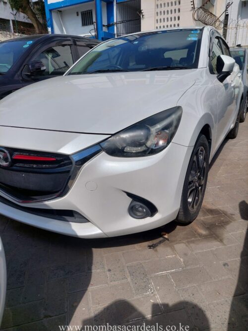 A white Mazda Demio parked at Mombasa Car Deals Ltd. Cars for sale in Mombasa.